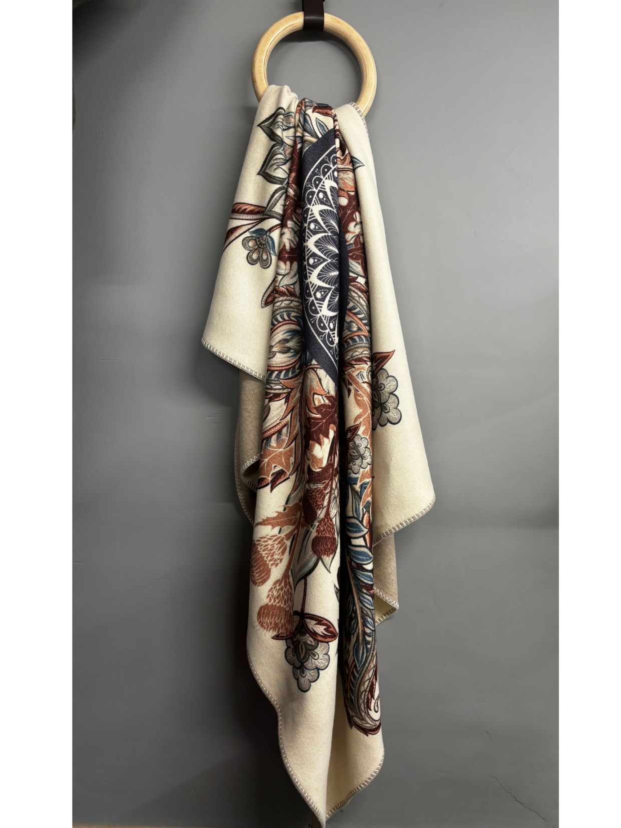 Patterned scarf draped over a wooden ring on a gray background