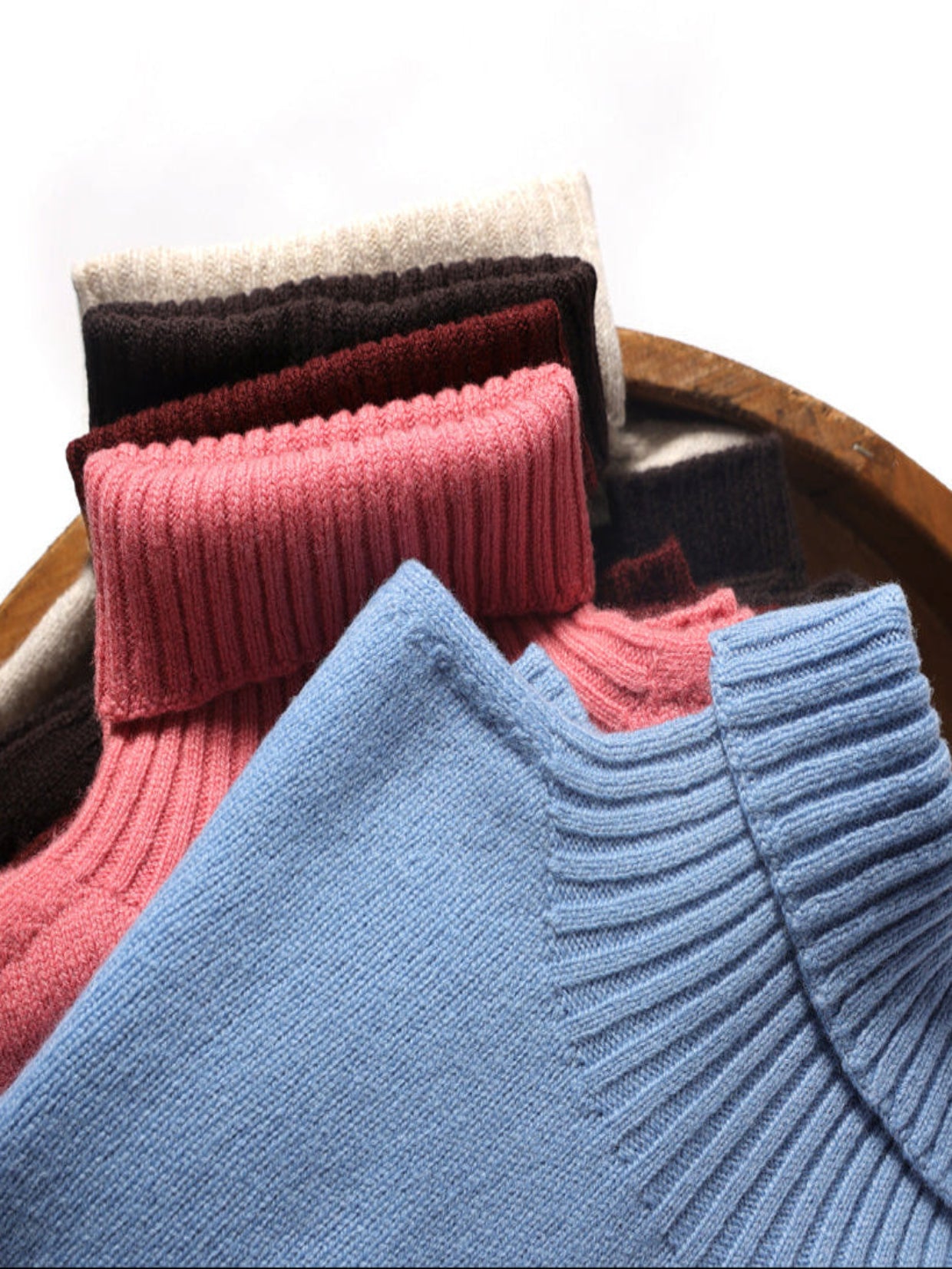 Stack of colorful folded sweaters on a wooden surface